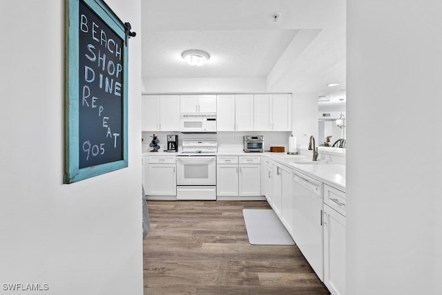 kitchen with sink, a barn door, dark hardwood / wood-style floors, white appliances, and white cabinets