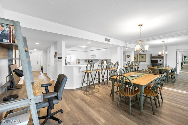 dining space with light hardwood / wood-style floors and a notable chandelier