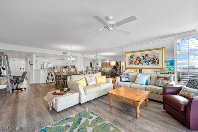 living room with hardwood / wood-style floors and ceiling fan with notable chandelier