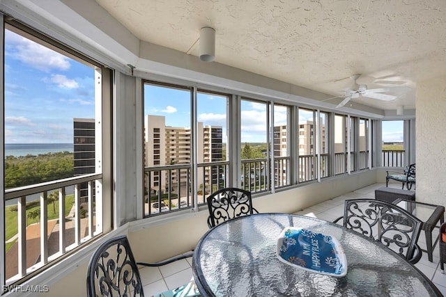 sunroom with ceiling fan, a healthy amount of sunlight, and a water view