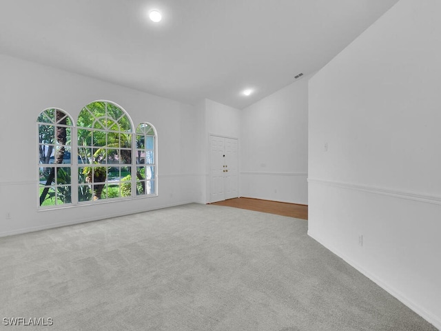 carpeted spare room with vaulted ceiling