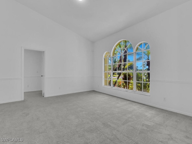 spare room featuring light colored carpet and lofted ceiling