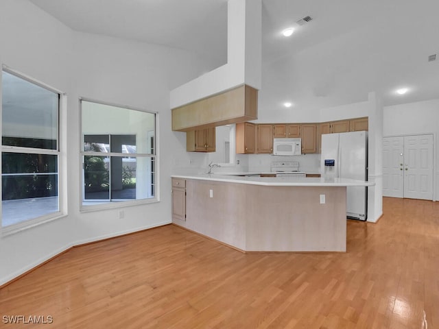 kitchen with light hardwood / wood-style floors, sink, white appliances, and kitchen peninsula