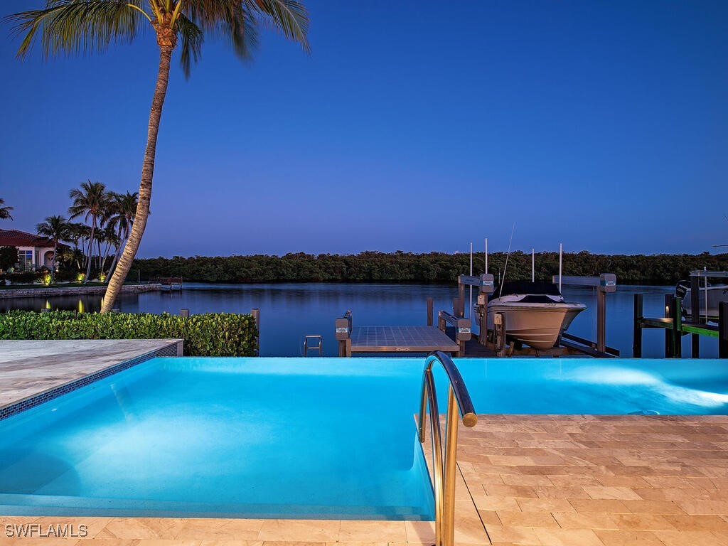 pool at dusk with a dock and a water view