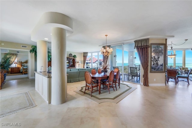 dining area featuring an inviting chandelier, a wall of windows, and ornate columns