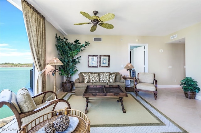 living room with ceiling fan and a water view