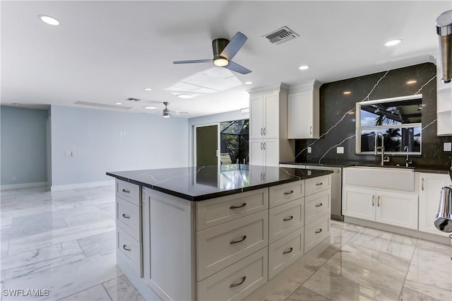 kitchen featuring white cabinets, ceiling fan, a center island, and tasteful backsplash