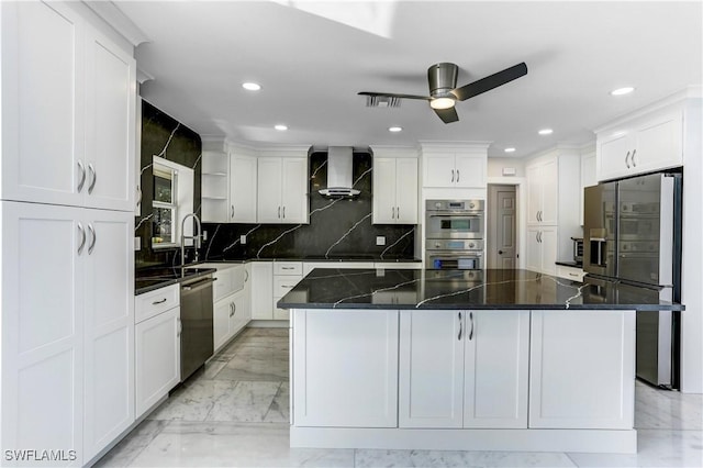 kitchen featuring dark stone counters, white cabinets, wall chimney exhaust hood, appliances with stainless steel finishes, and a large island