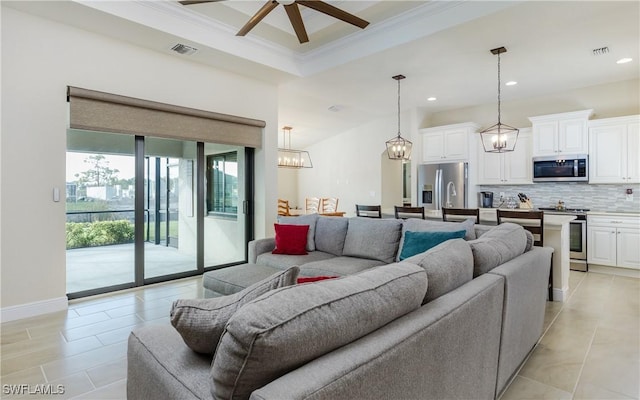 living room with a raised ceiling, ceiling fan, and ornamental molding