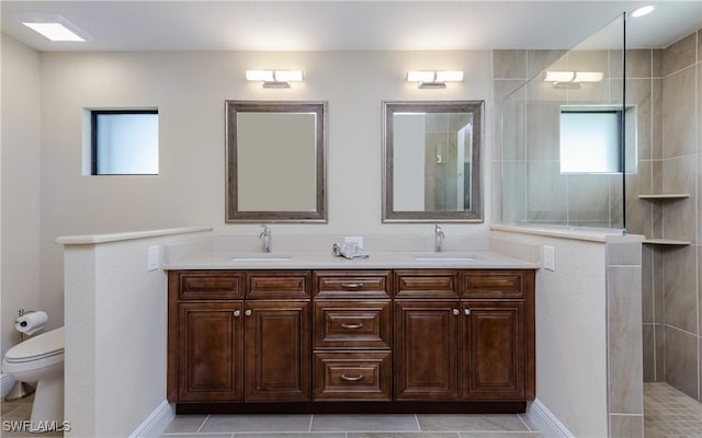 bathroom with tile patterned floors, toilet, a tile shower, and vanity