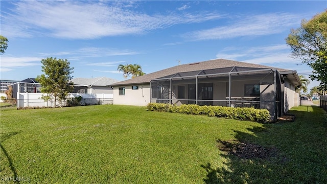 rear view of property with a lanai and a yard