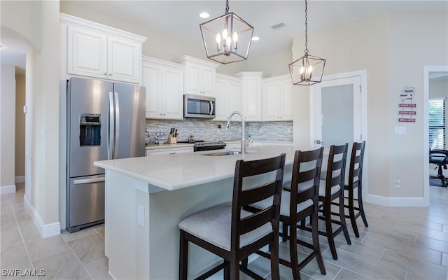 kitchen featuring white cabinetry, sink, hanging light fixtures, an island with sink, and appliances with stainless steel finishes