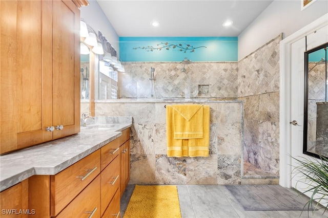 bathroom featuring vanity, walk in shower, and tile walls