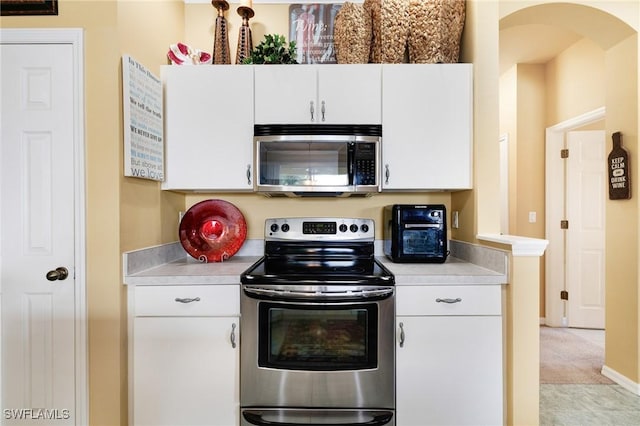 kitchen featuring white cabinetry, light carpet, and appliances with stainless steel finishes