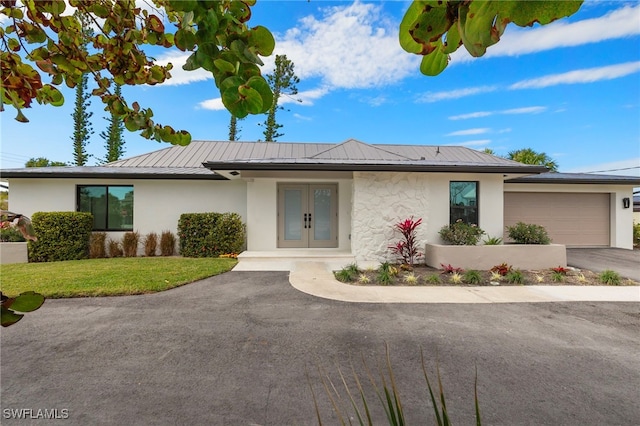 view of front of house featuring a front lawn, a garage, and french doors