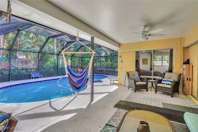 view of swimming pool featuring outdoor lounge area, ceiling fan, a patio, and glass enclosure