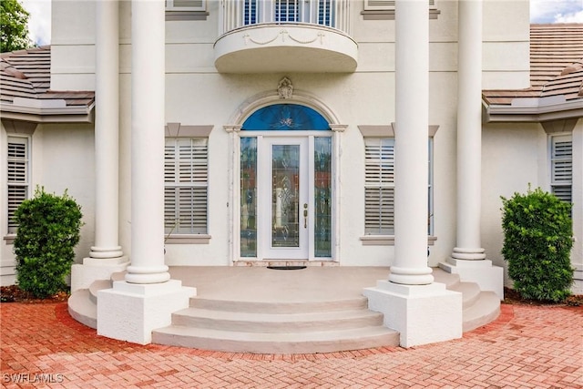 view of exterior entry with covered porch and a balcony