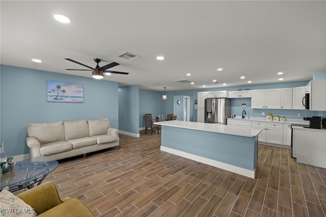 kitchen featuring appliances with stainless steel finishes, ceiling fan, decorative light fixtures, white cabinets, and a kitchen island