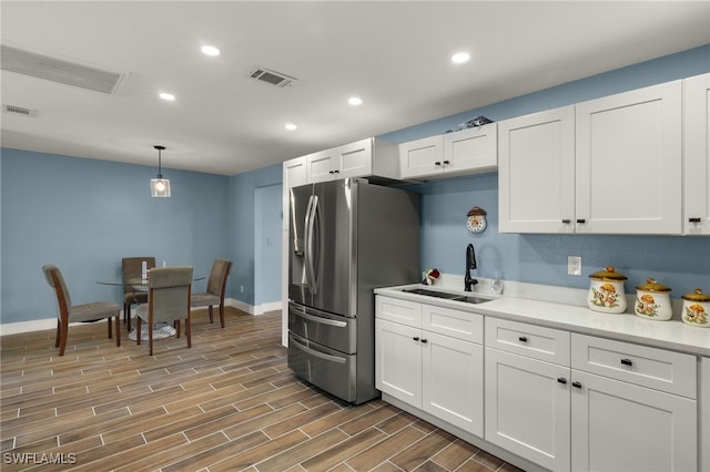 kitchen with stainless steel fridge with ice dispenser, sink, white cabinets, and pendant lighting