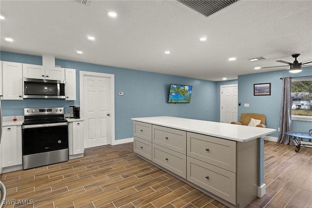 kitchen with appliances with stainless steel finishes, gray cabinetry, a kitchen island, ceiling fan, and white cabinetry