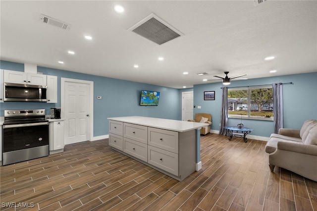 kitchen featuring ceiling fan, a center island, white cabinetry, and appliances with stainless steel finishes