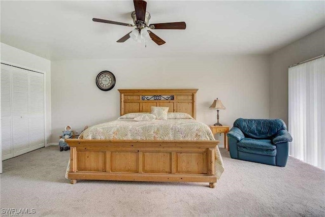 bedroom with ceiling fan, light carpet, and a closet