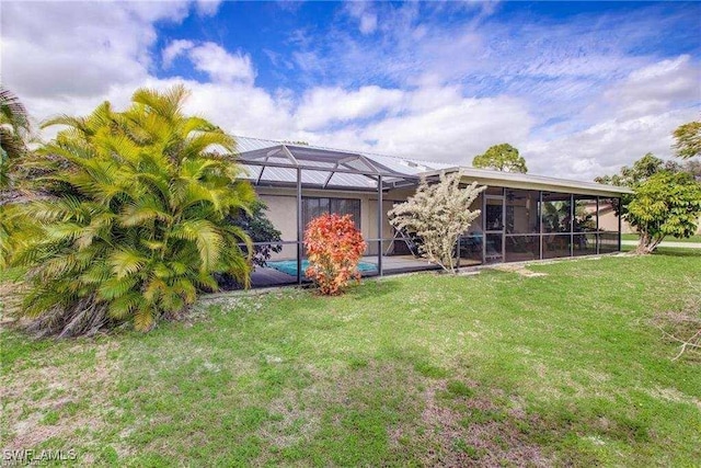 back of property featuring a lanai and a lawn