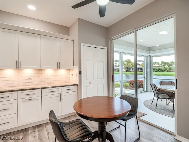 dining room featuring ceiling fan, light hardwood / wood-style floors, and a water view