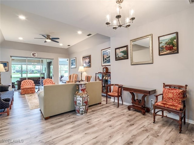 living room featuring ceiling fan with notable chandelier and light wood-type flooring