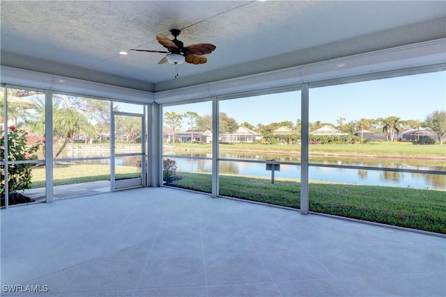 unfurnished sunroom featuring ceiling fan, a water view, and a wealth of natural light