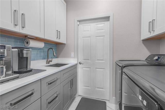 washroom with cabinets, washing machine and clothes dryer, and sink