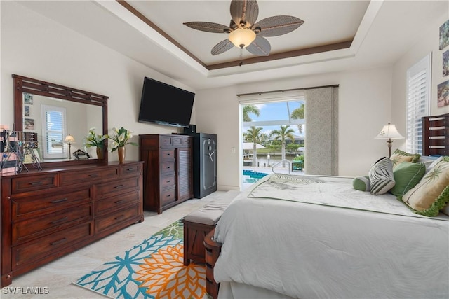 bedroom featuring ceiling fan, a tray ceiling, access to exterior, and multiple windows