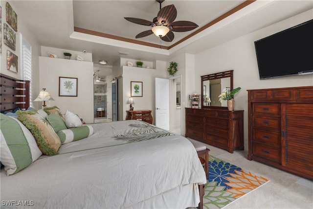 bedroom with connected bathroom, a tray ceiling, and ceiling fan