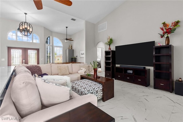 living room with ceiling fan with notable chandelier, high vaulted ceiling, and french doors