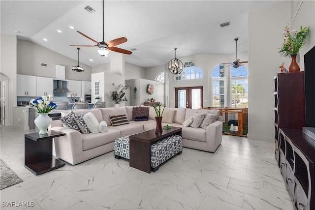 living room featuring ceiling fan with notable chandelier, high vaulted ceiling, and french doors