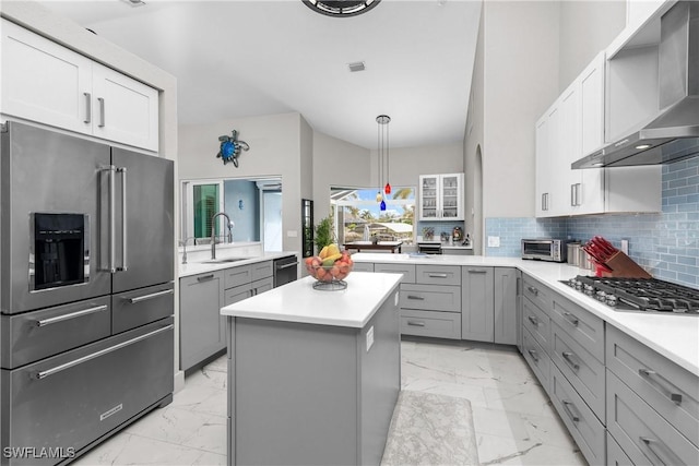 kitchen with sink, appliances with stainless steel finishes, a center island, tasteful backsplash, and wall chimney exhaust hood