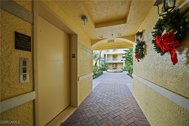 hall with a raised ceiling and elevator