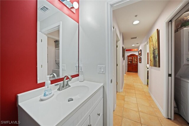 bathroom with tile patterned floors, vanity, and stacked washer and clothes dryer