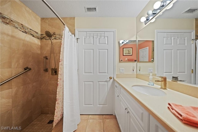 bathroom with tile patterned floors, vanity, walk in shower, and a textured ceiling