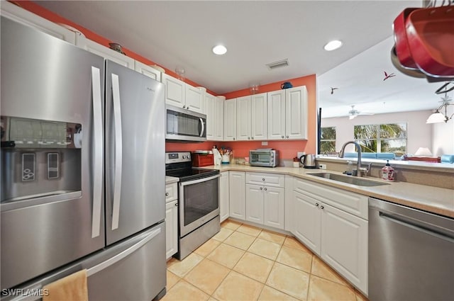 kitchen featuring sink, ceiling fan, light tile patterned flooring, white cabinetry, and stainless steel appliances