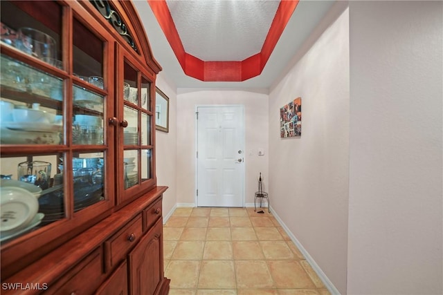 entryway with a textured ceiling and a tray ceiling