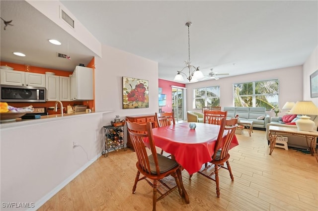 dining area featuring light hardwood / wood-style floors and ceiling fan with notable chandelier