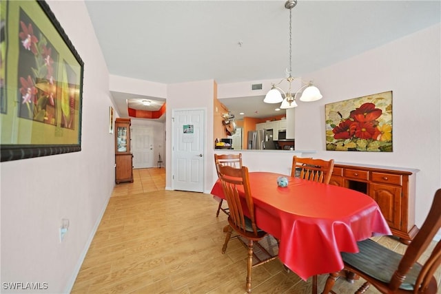 dining space with a chandelier and light hardwood / wood-style floors