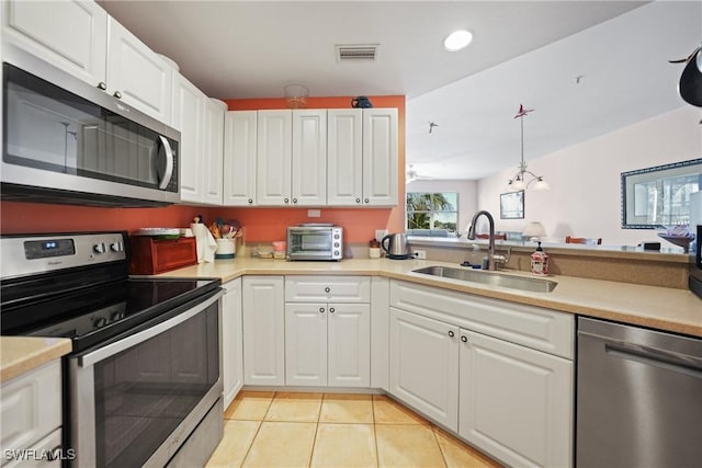 kitchen featuring hanging light fixtures, sink, light tile patterned floors, appliances with stainless steel finishes, and white cabinetry