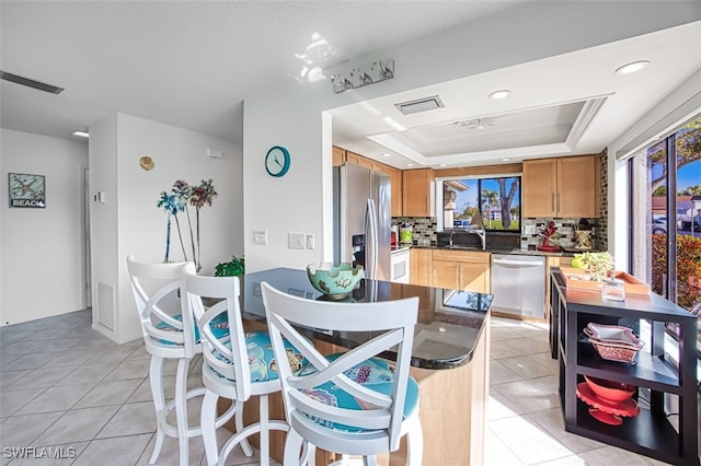 dining room featuring a tray ceiling, sink, and light tile patterned flooring