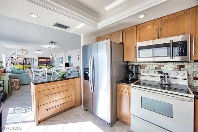 kitchen with decorative backsplash, appliances with stainless steel finishes, a tray ceiling, and ornamental molding