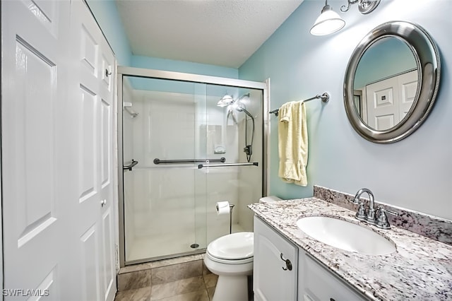 bathroom featuring a textured ceiling, vanity, toilet, and walk in shower