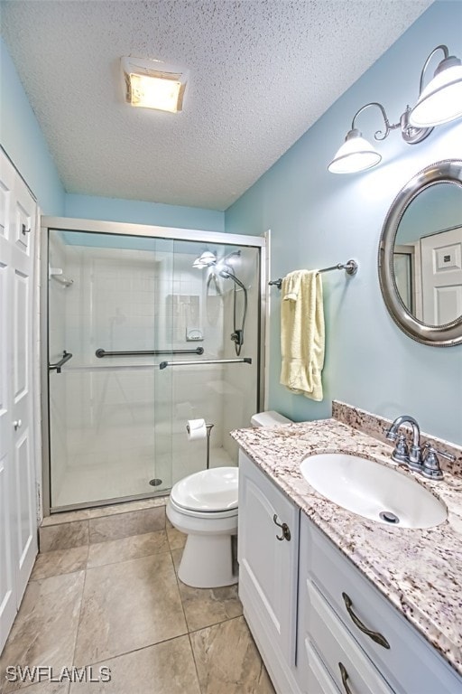 bathroom with an enclosed shower, vanity, toilet, and a textured ceiling