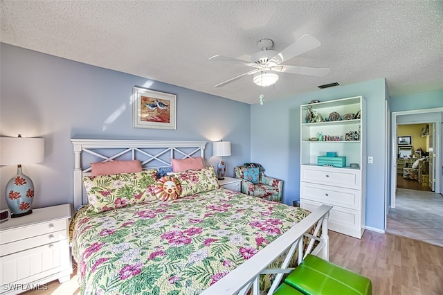 bedroom with ceiling fan, light wood-type flooring, and a textured ceiling