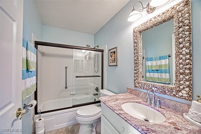 full bathroom featuring vanity, a textured ceiling, toilet, and bath / shower combo with glass door